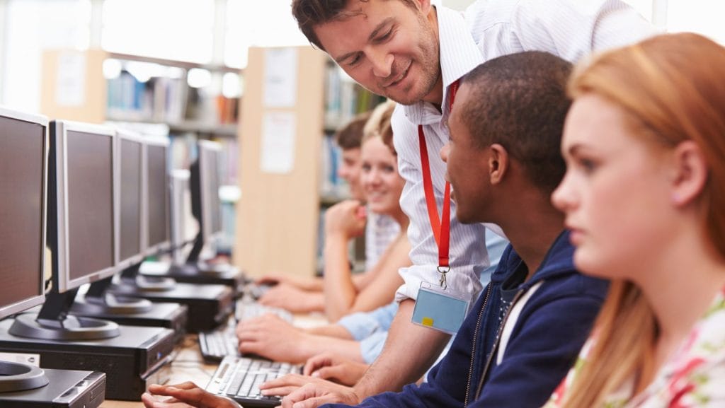 Teacher speaking with students in a computer lab
