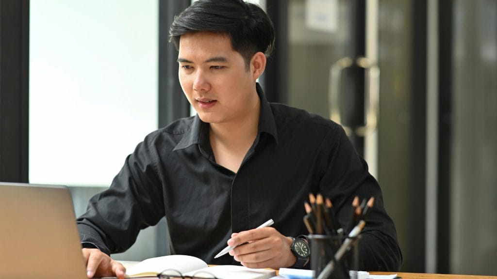 Photo of a young asian man working on a laptop